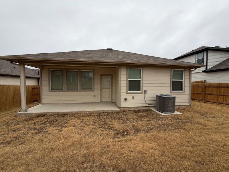 Rear view of property featuring a fenced backyard, a patio, and a shingled roof