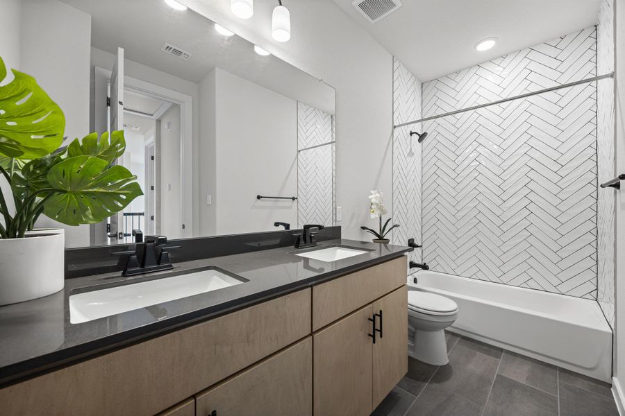 Full shared bath featuring double vanity and shower / bathtub combination