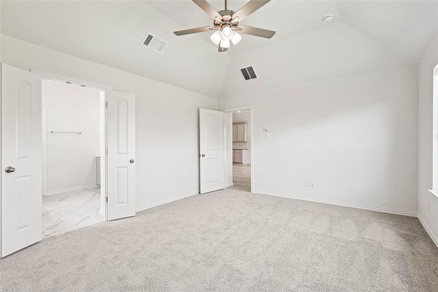 Unfurnished bedroom with ceiling fan, a walk in closet, light carpet, and a closet