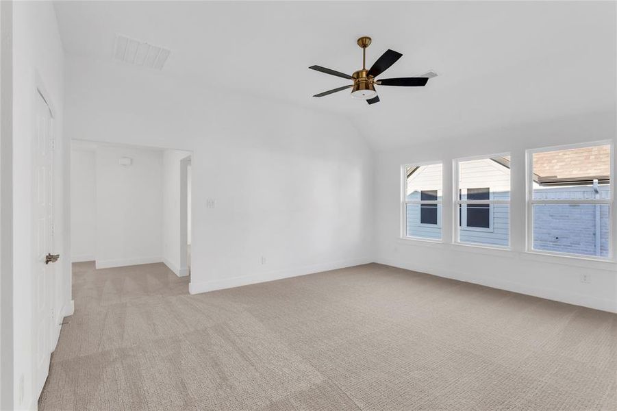 Spare room featuring light carpet, vaulted ceiling, and a ceiling fan