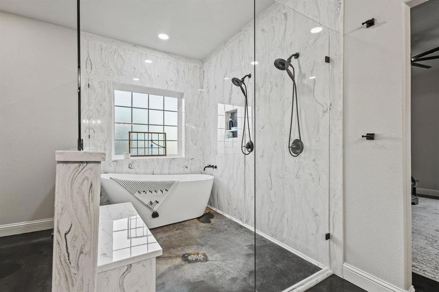 Bathroom featuring a freestanding bath, a marble finish shower, and concrete floors Bathroom featuring a freestanding bath, a marble finish shower, and concrete floors