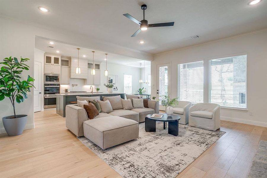 Living area with built in adjustable shelves, light engineered wood flooring, a stone fireplace with solid cedar mantle, ceiling fan, and french doors that open to a covered back patio. Living area with built in adjustable shelves, light engineered wood flooring, a stone fireplace with solid cedar mantle, ceiling fan, and french doors that open to a covered back patio.