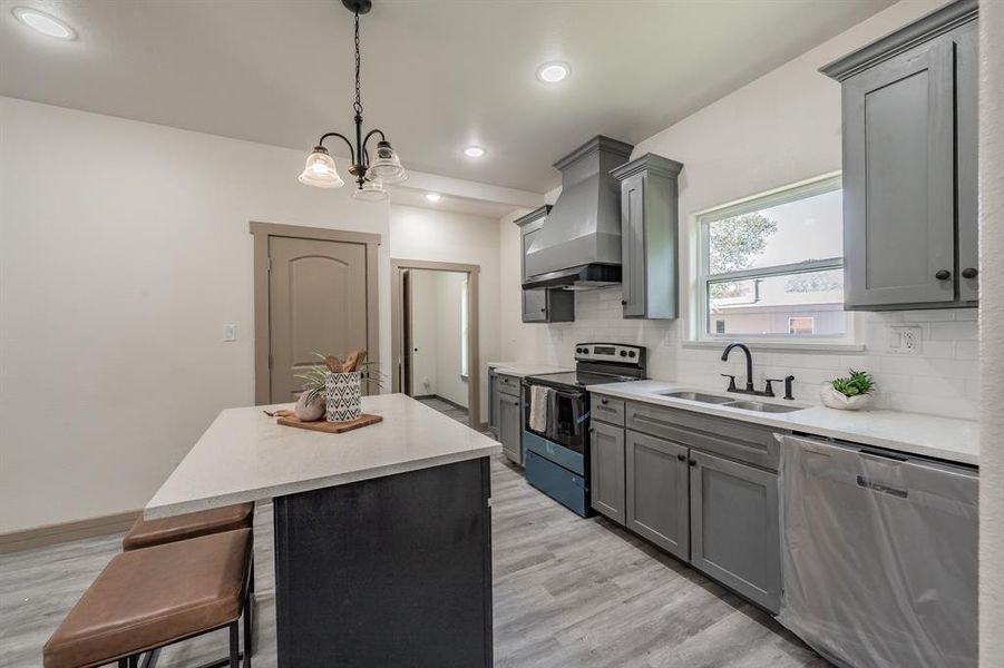 Kitchen with stainless steel appliances, hanging light fixtures, a kitchen island, tasteful backsplash, and a kitchen breakfast bar