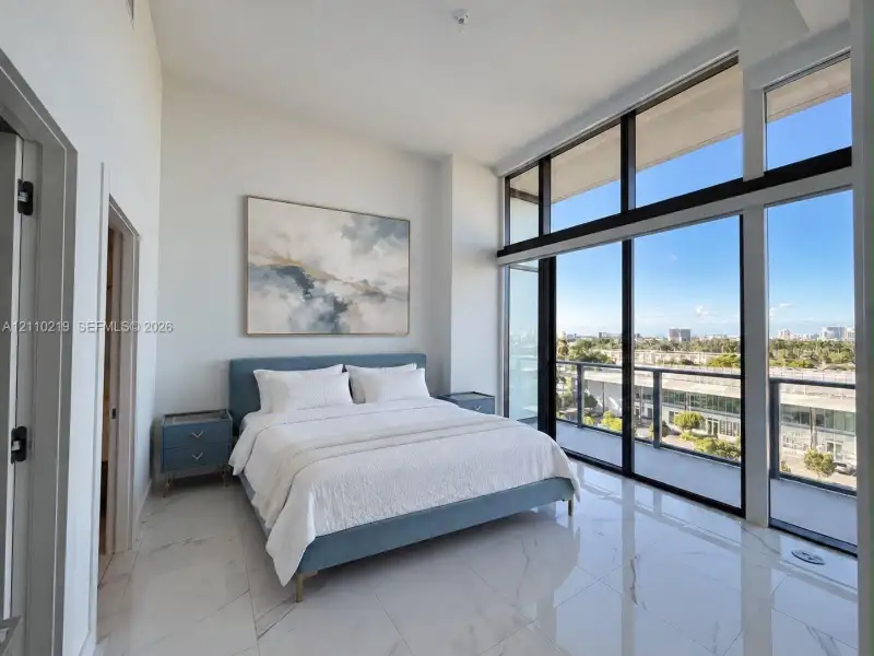 Floor-to-ceiling windows, high ceilings, large-format tile flooring, and a private balcony