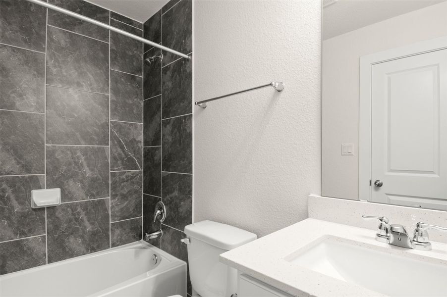 Full bathroom with toilet, a textured wall, tub / shower combination, and vanity