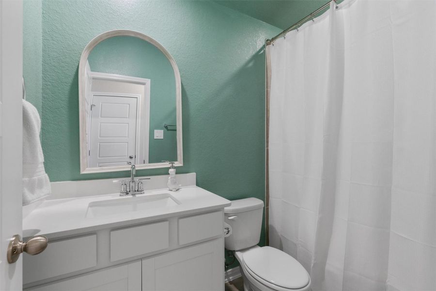 Bathroom featuring a white vanity with an integrated sink, polished chrome faucet, and an arched framed mirror Bathroom featuring a white vanity with an integrated sink, polished chrome faucet, and an arched framed mirror