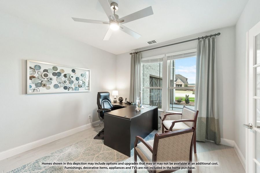 Home office with dark desk, leather chair, ceiling fan, and large window with natural light