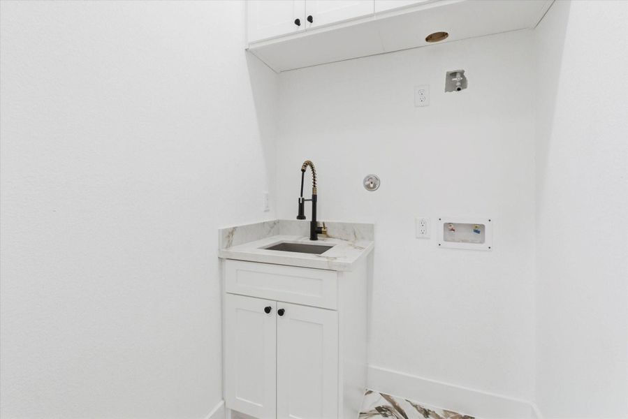 Downstairs laundry room fully equipped with a utility sink and abundant cabinetry for storage and organization.