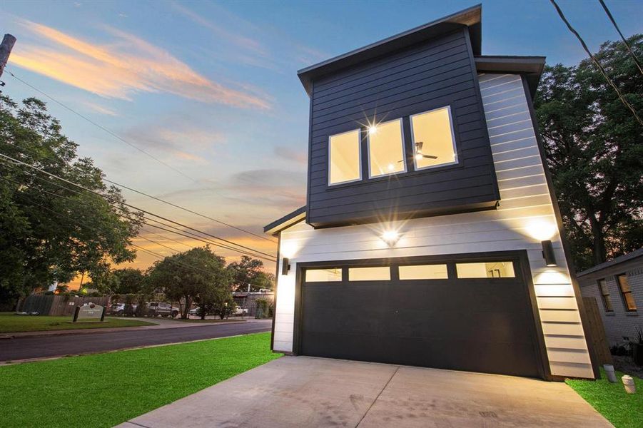 View of front of property featuring concrete driveway, a yard, and a garage