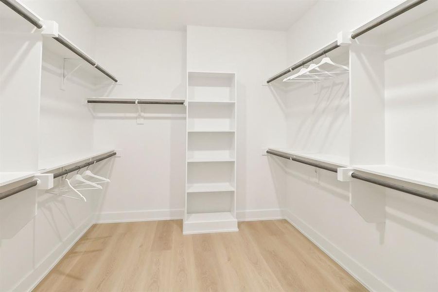 Primary Walk in closet featuring light wood finished floors