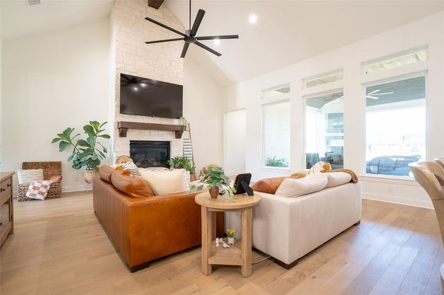 Living area with ceiling fan, light wood-style flooring, a fireplace, and lofted ceiling