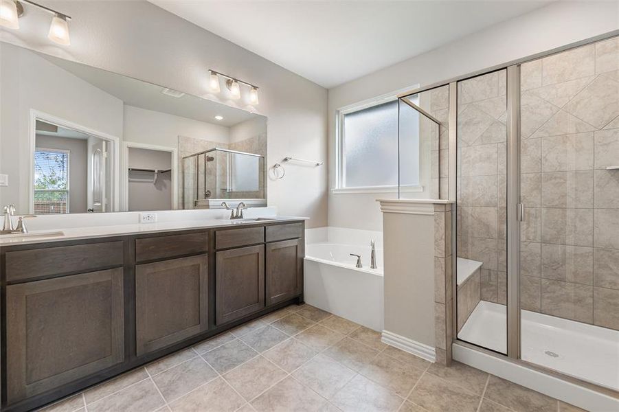 Bathroom featuring double vanity, a shower stall, a garden tub, a walk in closet, and light tile patterned floors Bathroom featuring double vanity, a shower stall, a garden tub, a walk in closet, and light tile patterned floors