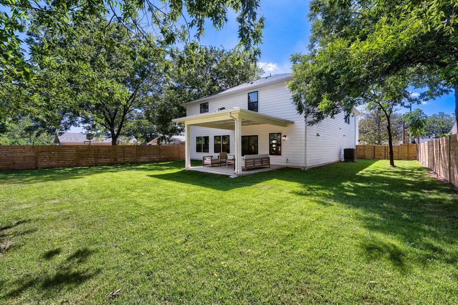 A spacious backyard with mature trees, a manicured lawn, and a covered patio perfect for outdoor living. A spacious backyard with mature trees, a manicured lawn, and a covered patio perfect for outdoor living.