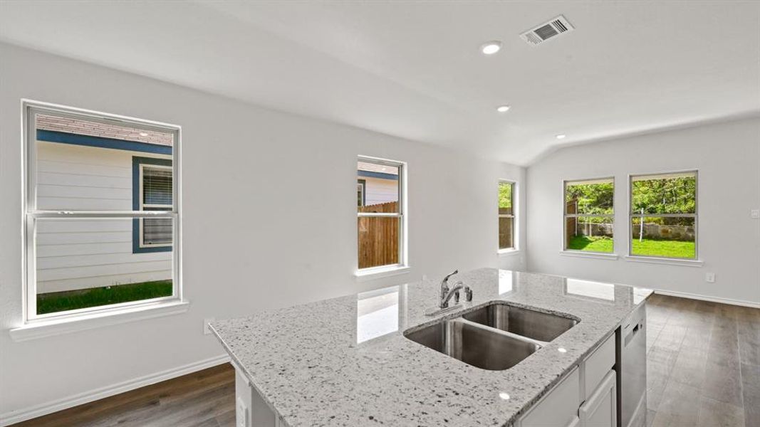 Kitchen island featuring a dual stainless steel sink, chrome faucet, and speckled countertop
