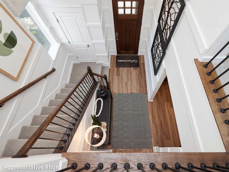 Entryway featuring a wood door with glass inserts, hardwood flooring, and a carpeted staircase with a dark wood handrail and black balusters