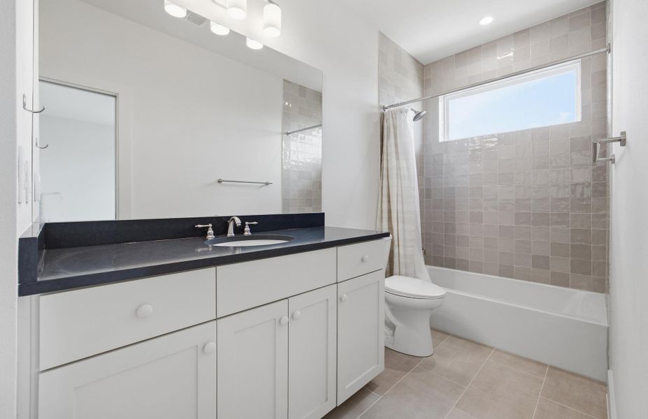 Full bath with vanity, shower / bath combo with custom tile and quartz counters