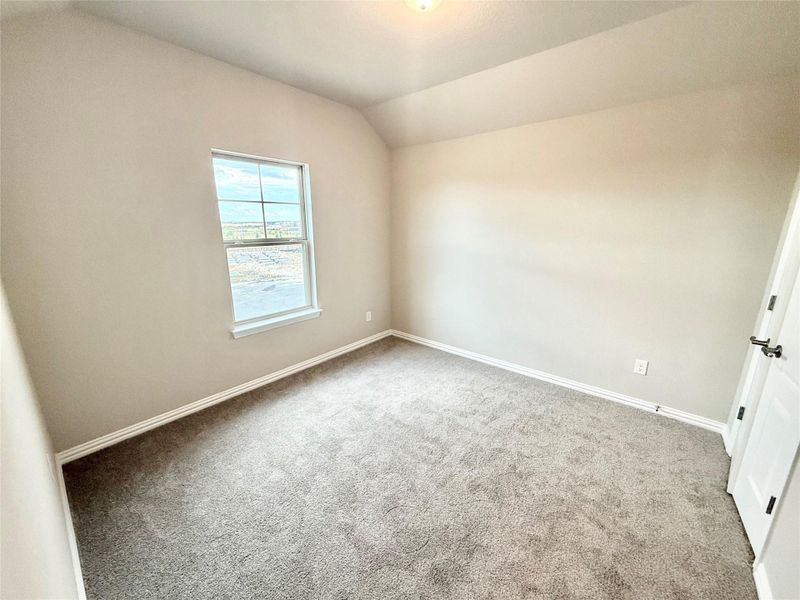 Unfurnished bedroom featuring vaulted ceiling and carpet flooring Unfurnished bedroom featuring vaulted ceiling and carpet flooring