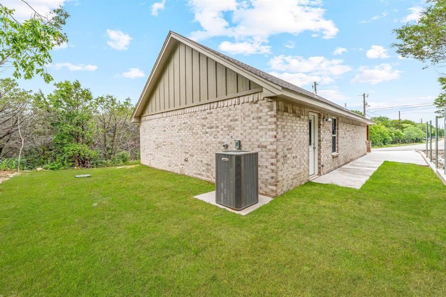 View of side of home featuring board and batten siding, central air condition unit, a lawn, and brick siding View of side of home featuring board and batten siding, central air condition unit, a lawn, and brick siding