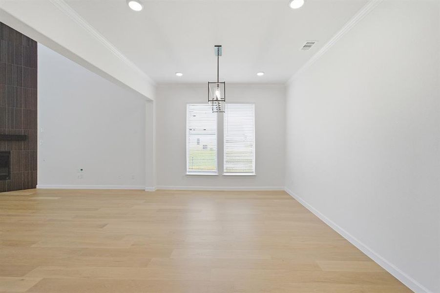 Spacious interior with light wood-finish flooring, recessed lighting, and a contemporary chandelier