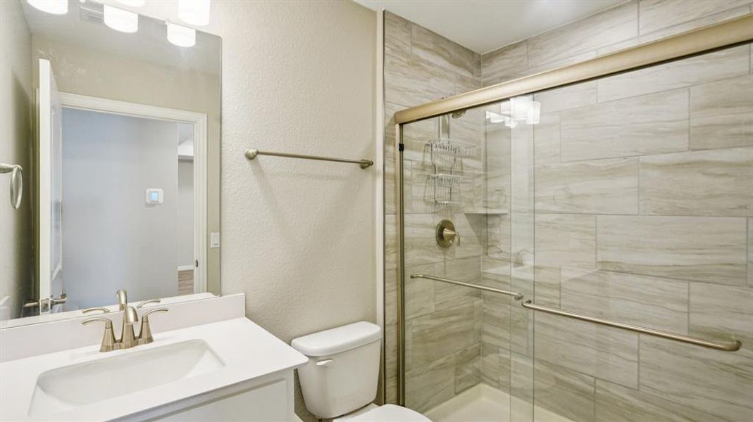 Bathroom featuring a textured wall, a shower stall, and vanity Bathroom featuring a textured wall, a shower stall, and vanity