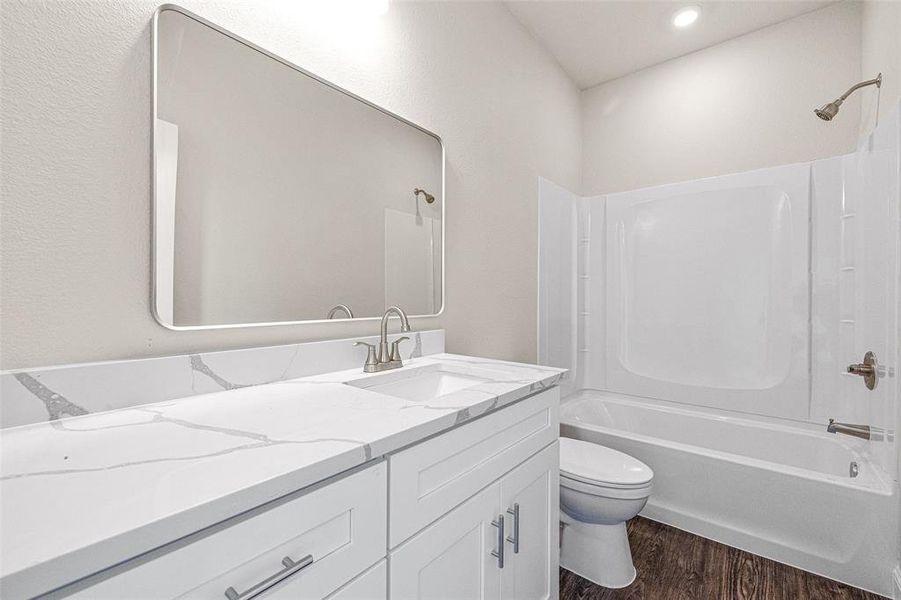 Full bathroom with toilet, hardwood / wood-style flooring, shower / washtub combination, and vanity