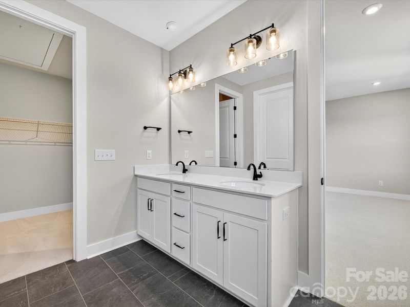 Dual vanity primary bathroom with a walk-in closet