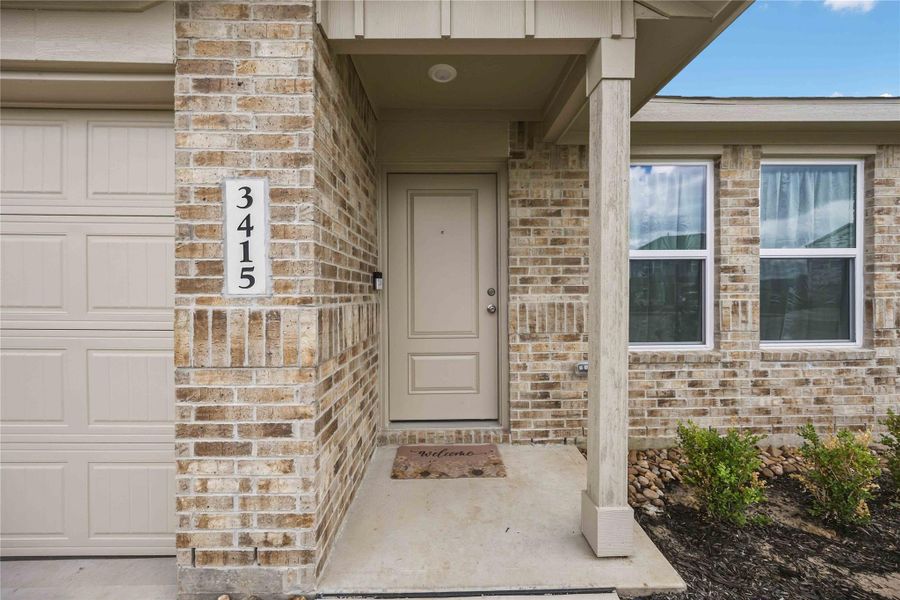 Charming brick exterior with a welcoming entryway, highlighted by a neutral front door and tidy landscaping.
