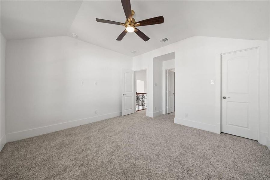 Bedroom with vaulted ceiling, light colored carpet, and ceiling fan Bedroom with vaulted ceiling, light colored carpet, and ceiling fan