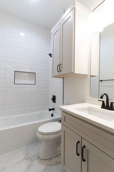 Full bath featuring vanity, marble look tiles, and shower / washtub combination Full bath featuring vanity, marble look tiles, and shower / washtub combination