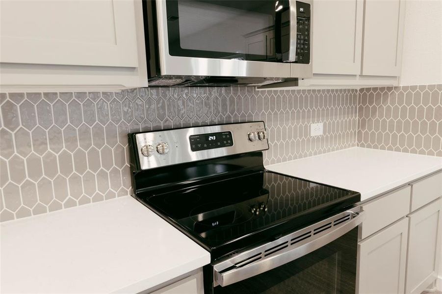 Kitchen with white cabinets, stainless steel appliances, and tasteful backsplash