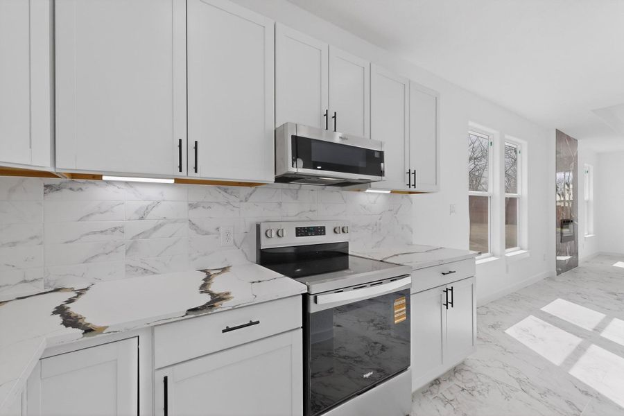 Kitchen with stainless steel appliances, quartz countertops, and white cabinetry