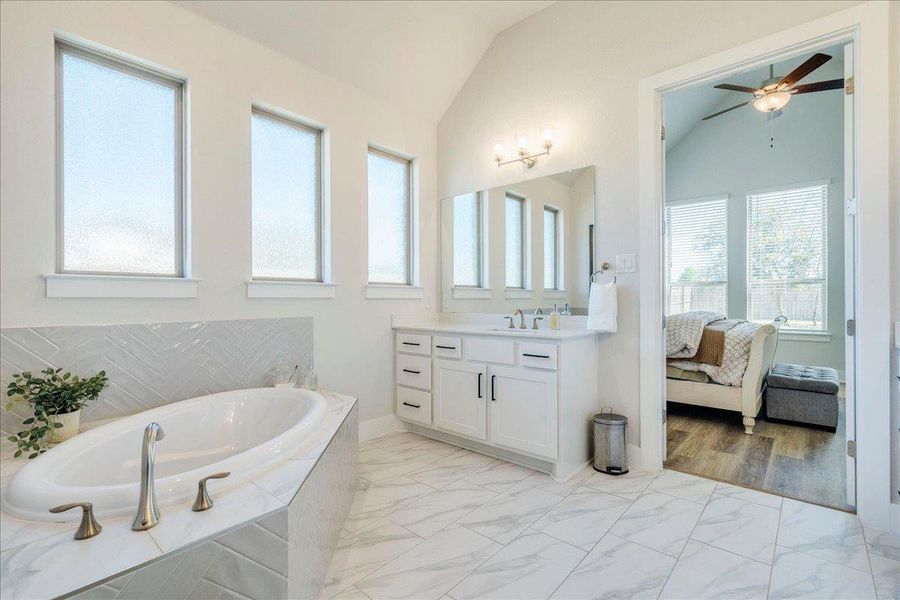 Bathroom with ensuite bathroom, vanity, a garden tub, ceiling fan, and lofted ceiling Bathroom with ensuite bathroom, vanity, a garden tub, ceiling fan, and lofted ceiling