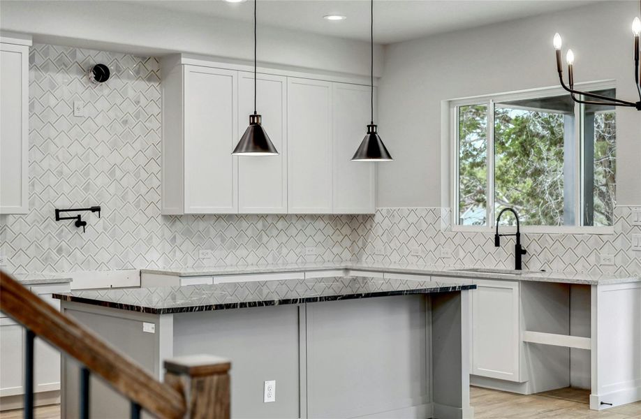 Kitchen featuring a sink, white cabinets, dark stone counters, tasteful backsplash, and pendant lighting