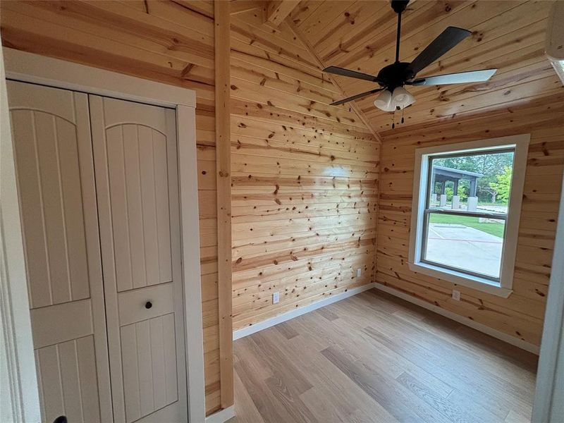 Unfurnished bedroom with wooden walls, light wood-style flooring, wooden ceiling, and a closet Unfurnished bedroom with wooden walls, light wood-style flooring, wooden ceiling, and a closet