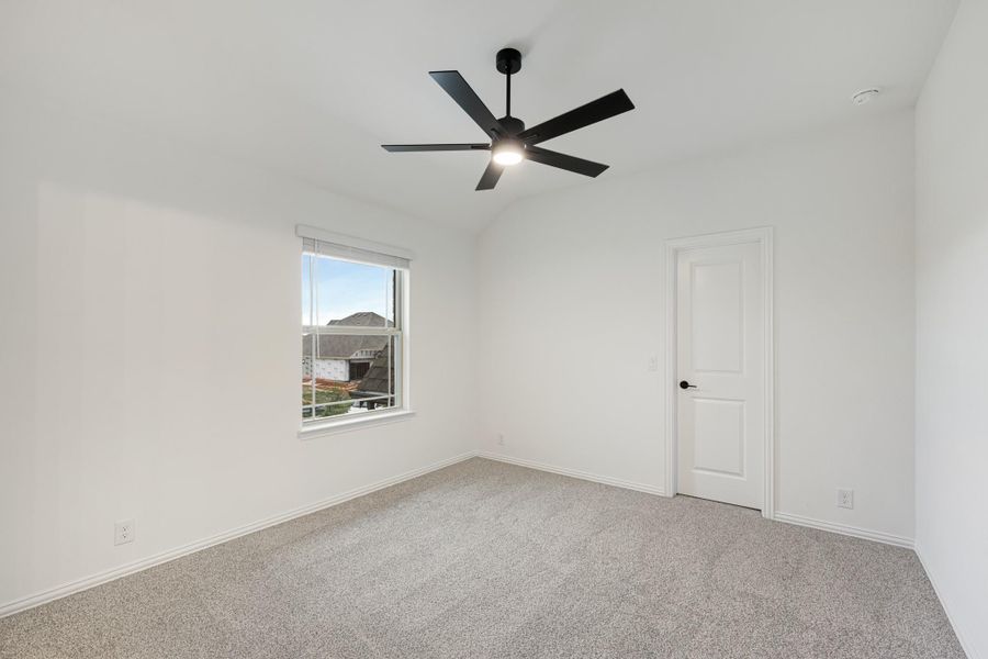 Empty bedroom with gray carpet, white walls, black ceiling fan, and single window
