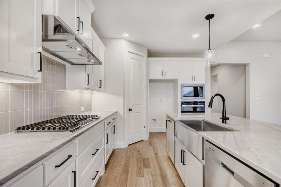 Kitchen with light stone countertops, white cabinetry, and stainless steel appliances