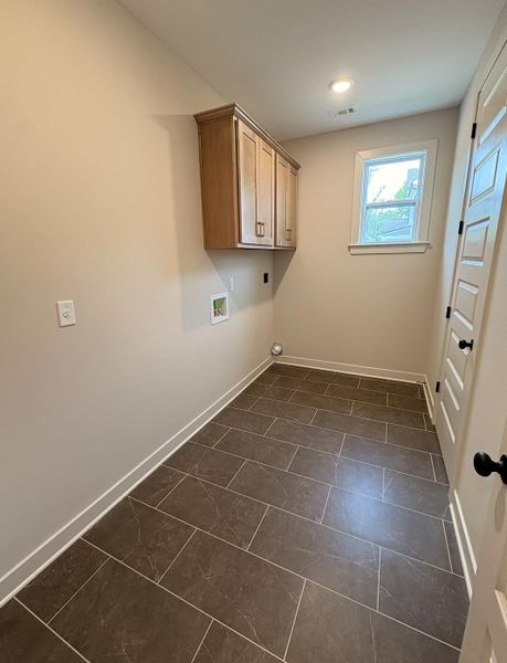Utility room featuring dark rectangular floor tiles and light-colored walls