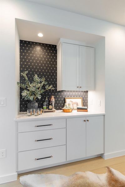 Bar with white cabinetry, tasteful backsplash, light wood finished floors, recessed lighting, and light stone countertops
