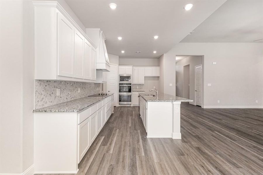 Kitchen with backsplash, light stone countertops, white cabinetry, recessed lighting, and light wood-type flooring Kitchen with backsplash, light stone countertops, white cabinetry, recessed lighting, and light wood-type flooring