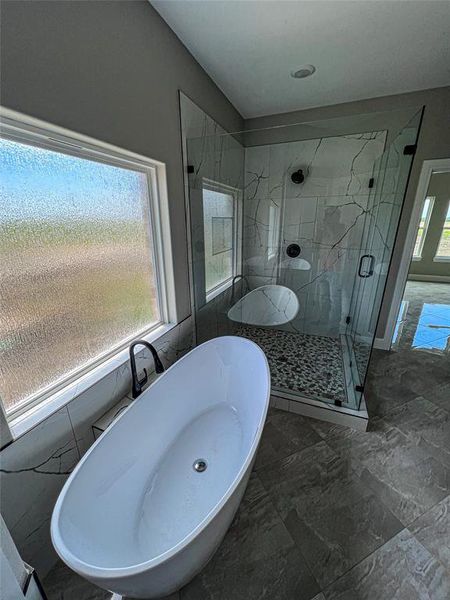 Bathroom featuring separate shower and tub, a healthy amount of sunlight, and tile patterned floors