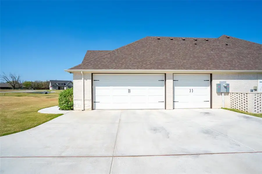 View of side of home featuring brick siding, a garage, driveway, roof with shingles, and a yard View of side of home featuring brick siding, a garage, driveway, roof with shingles, and a yard