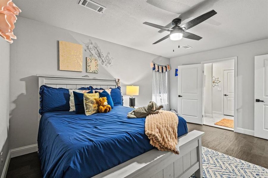Bedroom with dark wood-type flooring, ceiling fan, and a textured ceiling Bedroom with dark wood-type flooring, ceiling fan, and a textured ceiling