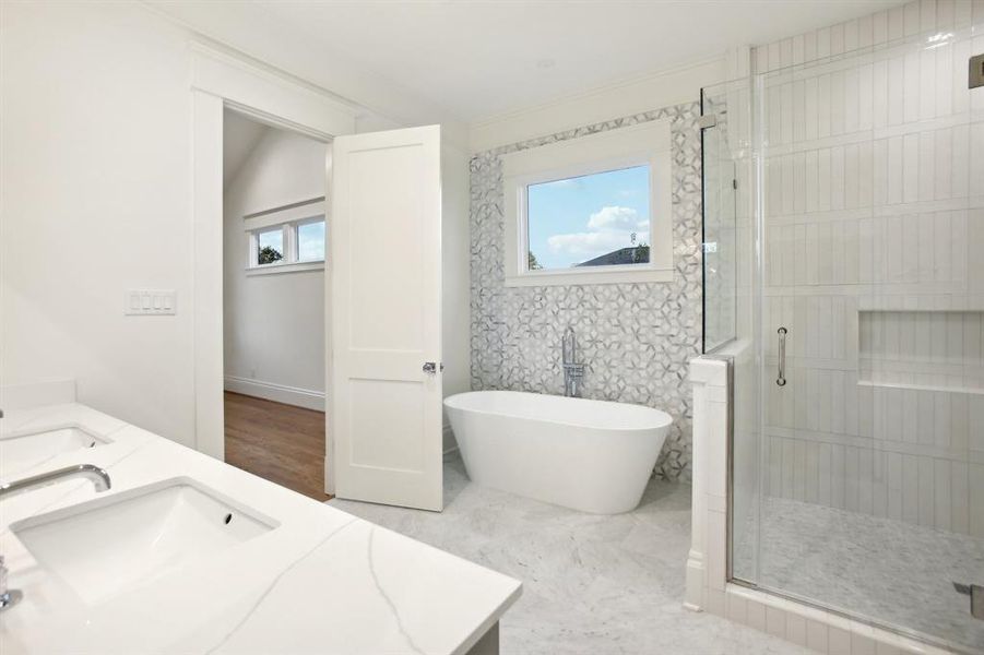 The tub is set in front of a marble mosaic tile, and the shower features a stacked subway design with a horizontal breaker.