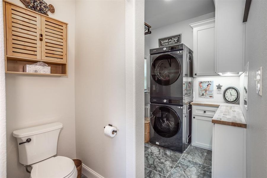 Laundry room with stacked washer and dryer, counterspace and cabinets