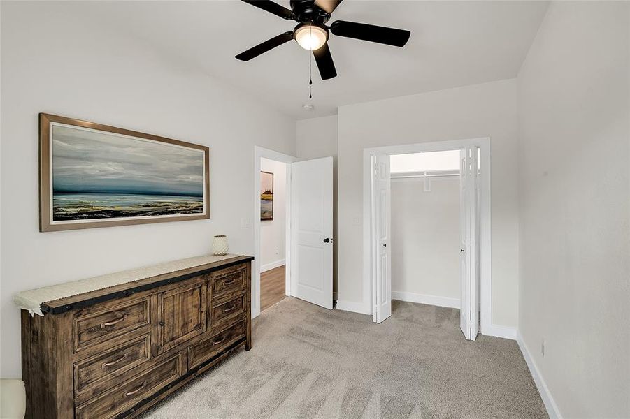 Bedroom featuring a closet, light colored carpet, and ceiling fan