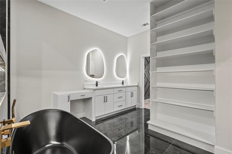 Bathroom featuring double vanity, a freestanding bath, and granite floors