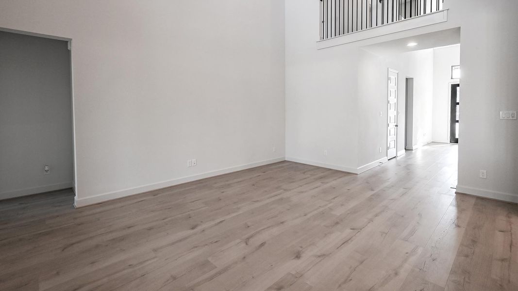 Spare room featuring light wood-type flooring and a towering ceiling Spare room featuring light wood-type flooring and a towering ceiling