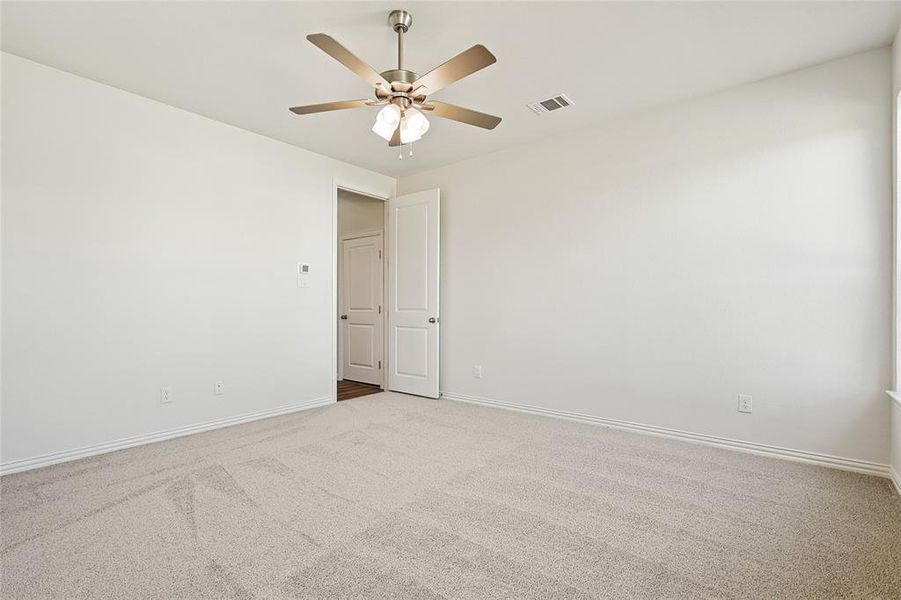 Carpeted spare room featuring ceiling fan