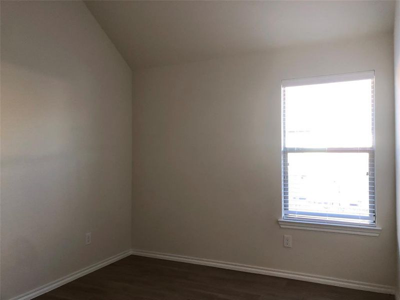 Unfurnished room with dark hardwood / wood-style flooring and lofted ceiling