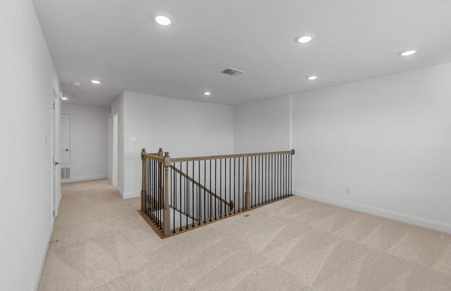 Corridor with an upstairs landing, recessed lighting, and light colored carpet